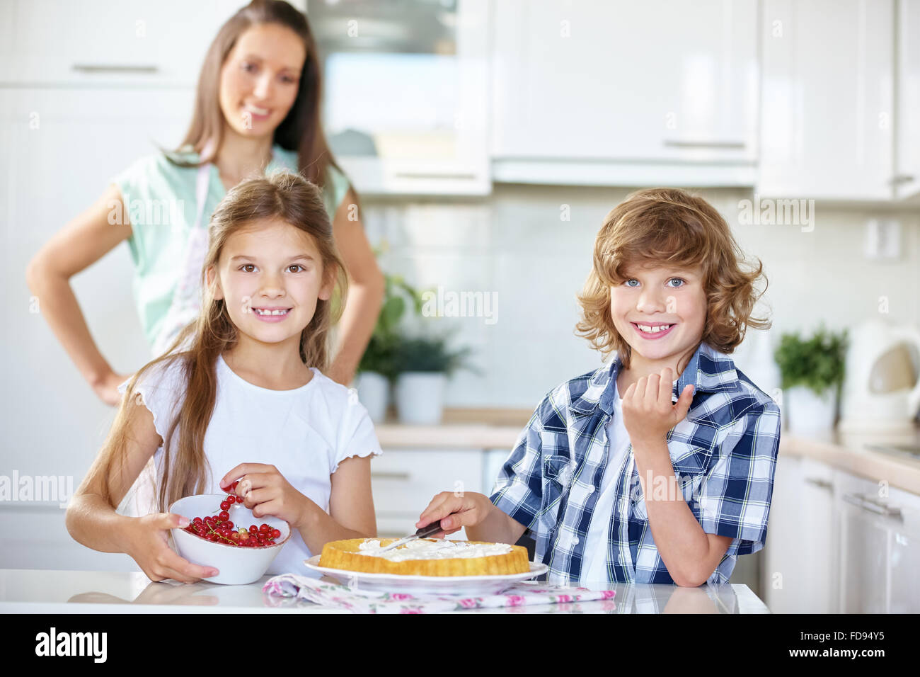 Deux enfants la confection d'un gâteau aux fruits frais avec groseilles rouges dans la cuisine Banque D'Images