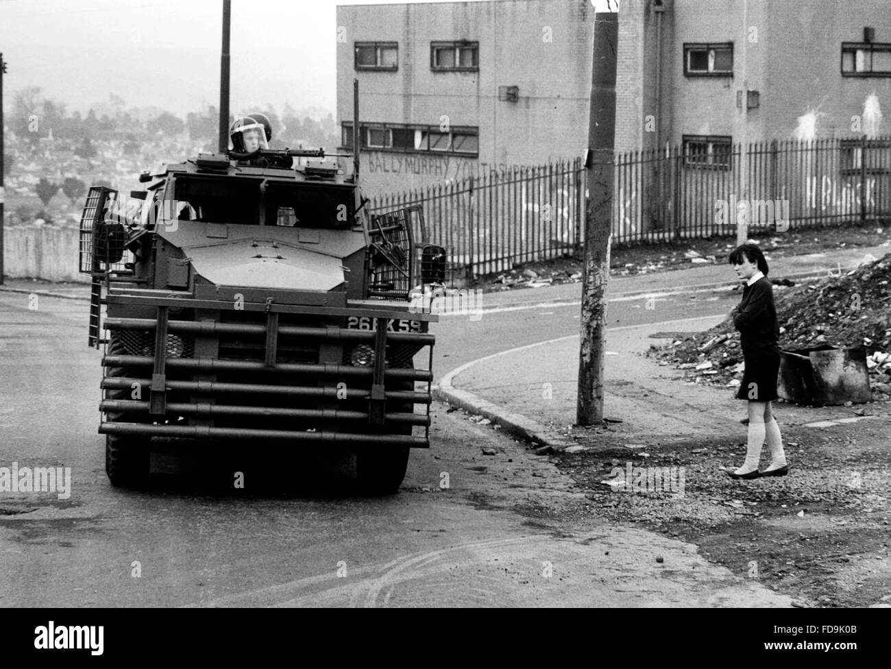 Un véhicule blindé, connu sous le nom de 'pig' dans le Régiment de Queens en patrouille passe une écolière en uniforme à Belfast , Irlande du Nord en avril 1984 . Près de 2000 soldats du régiment avec plus de 200 de la Sussex étaient stationnés en Irlande à l'époque Banque D'Images