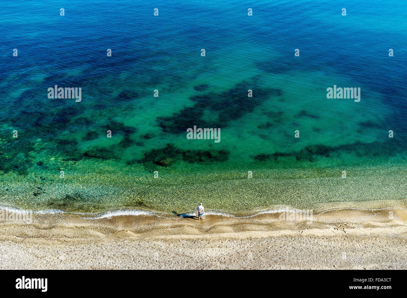Homme debout seule sur une plage au bord de l'eau, Sicile, Italie Banque D'Images