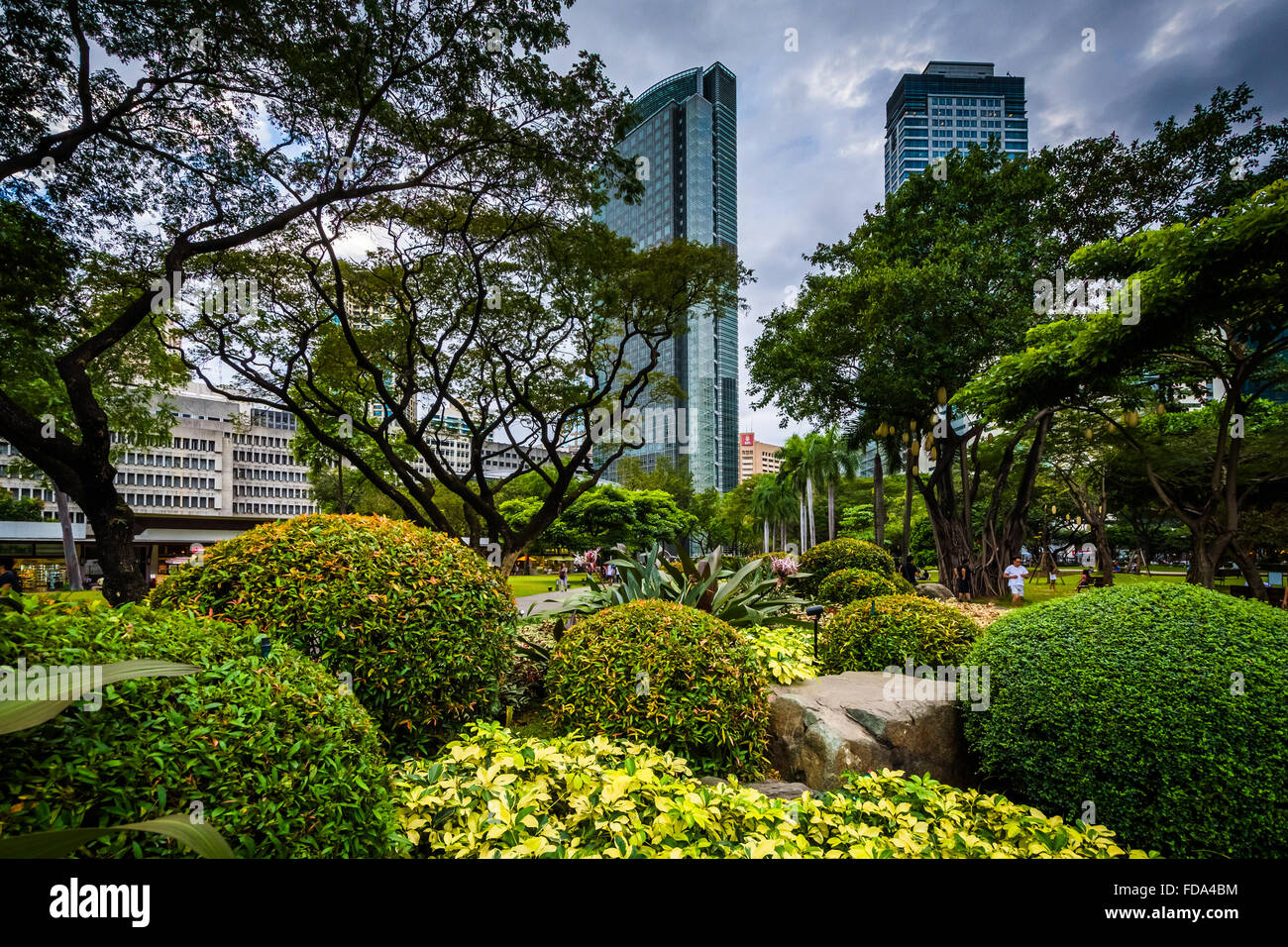 Jardins et des gratte-ciel vu à Ayala Triangle Park, à Makati, Metro Manila. Banque D'Images