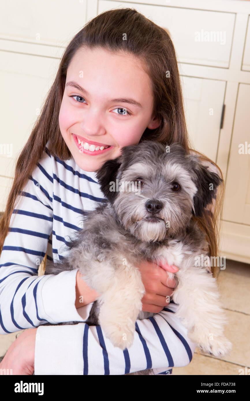 Jeune fille tenant un chiot. Elle est à la recherche à la caméra et sourit. Banque D'Images