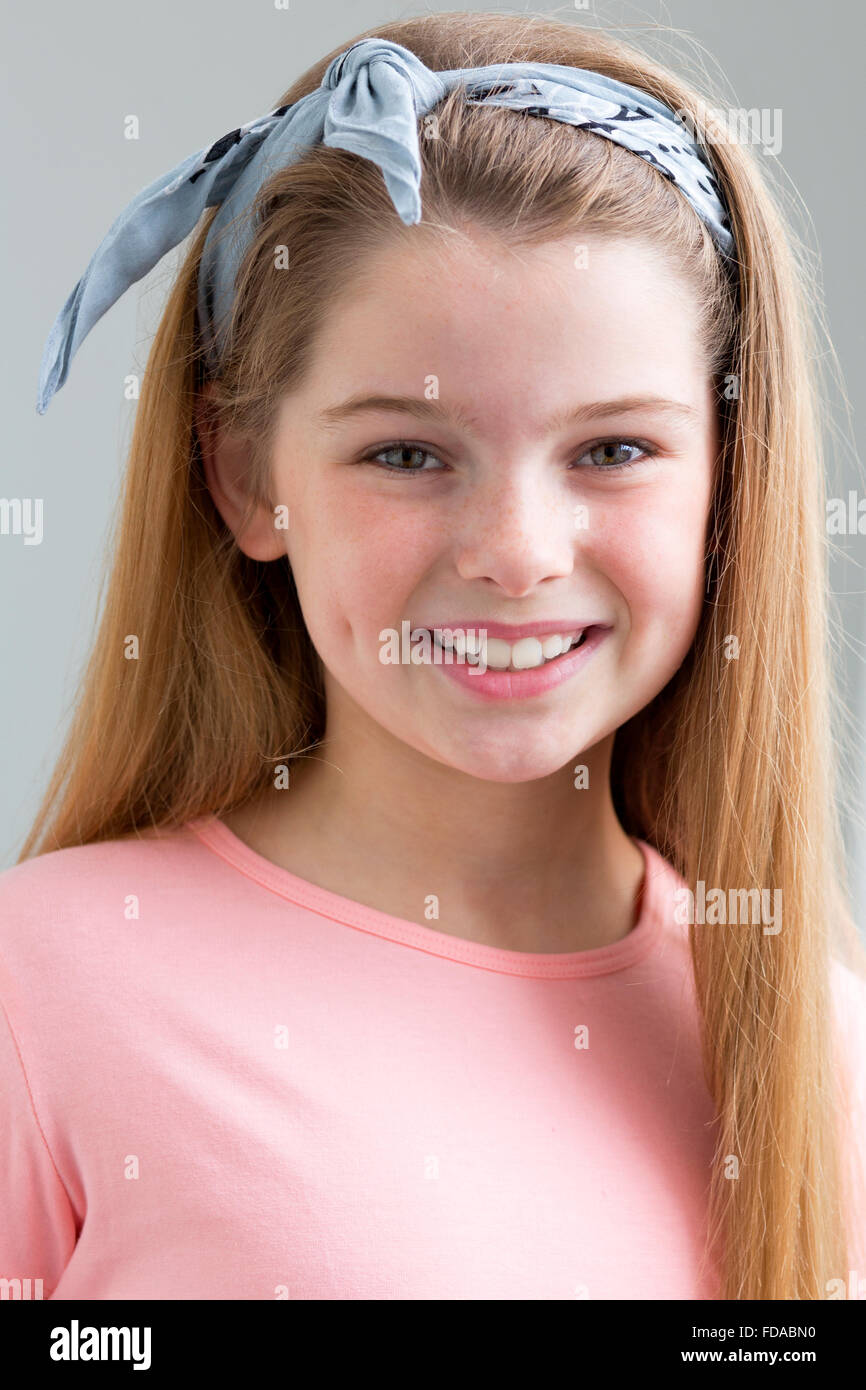 Un portrait d'une jeune fille avec un fond gris. Elle est à la recherche à la caméra et sourit. Banque D'Images