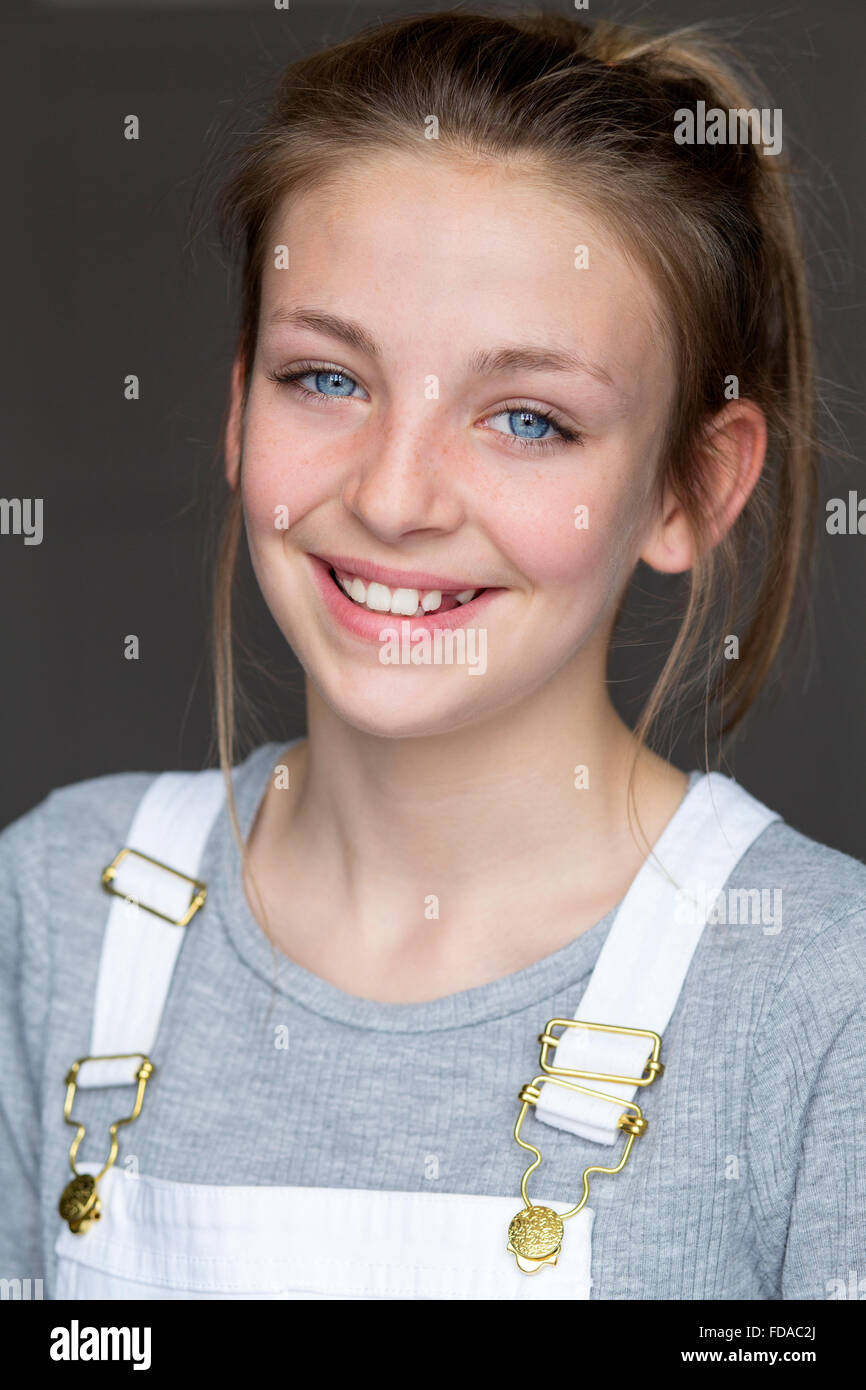 Portrait d'une jeune fille avec un fond gris. Elle porte des vêtements décontractés et souriant à la caméra. Banque D'Images