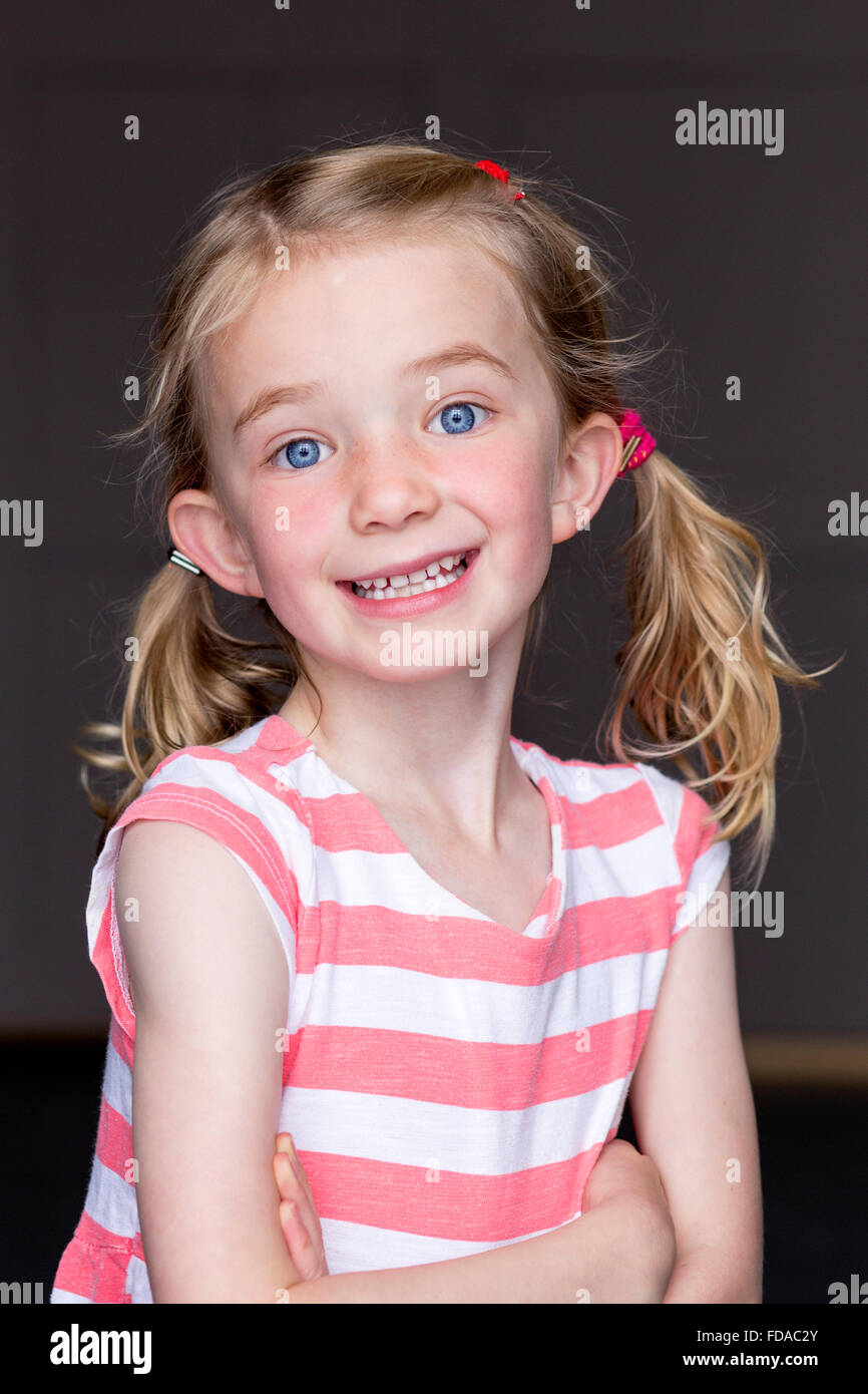 Portrait d'une jeune fille avec un fond gris. Elle sourit et regardant la caméra. Banque D'Images