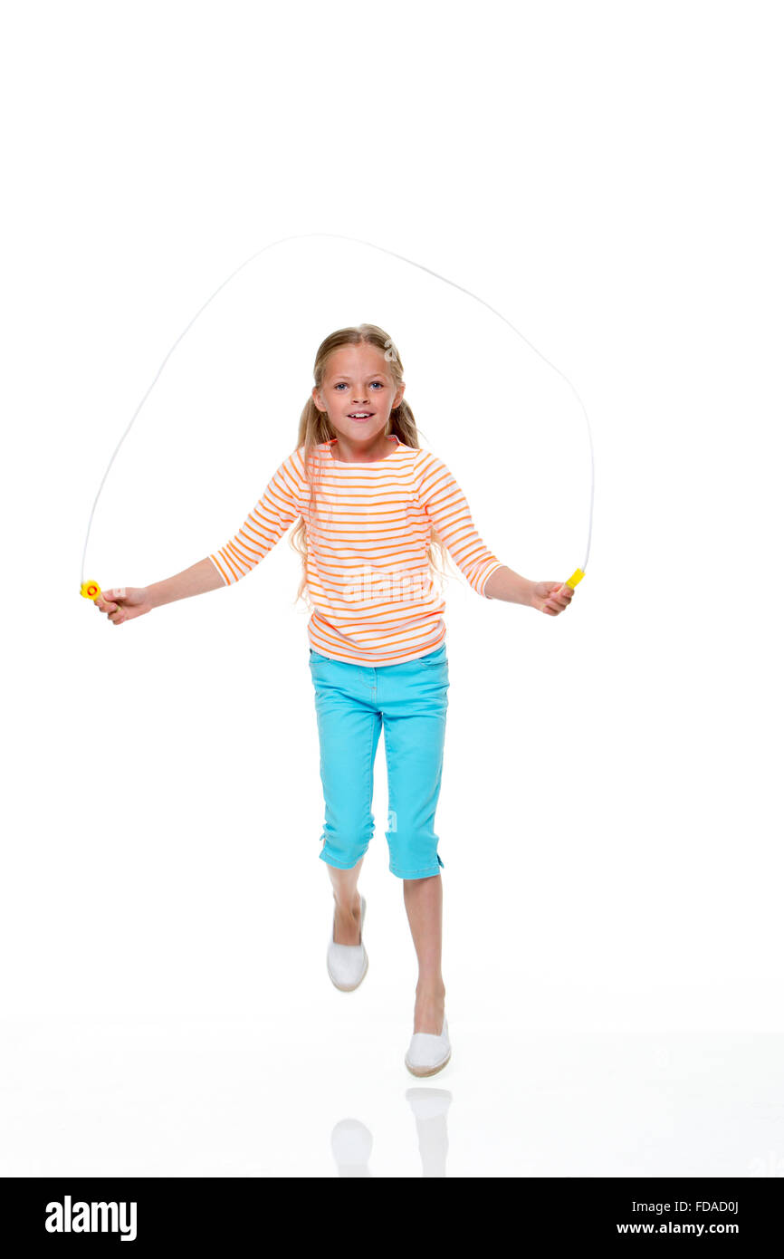 Portrait d'une jeune fille sautant avec un fond blanc. Elle porte des vêtements décontractés et regardant la caméra et sourit. Banque D'Images
