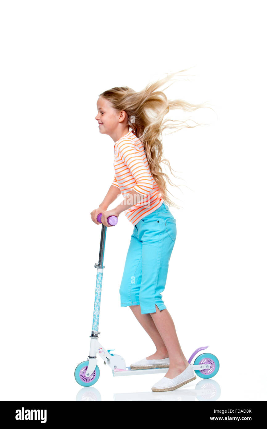 Portrait d'une jeune fille sur son scooter avec un fond blanc. Elle porte des vêtements décontractés et souriants. Banque D'Images