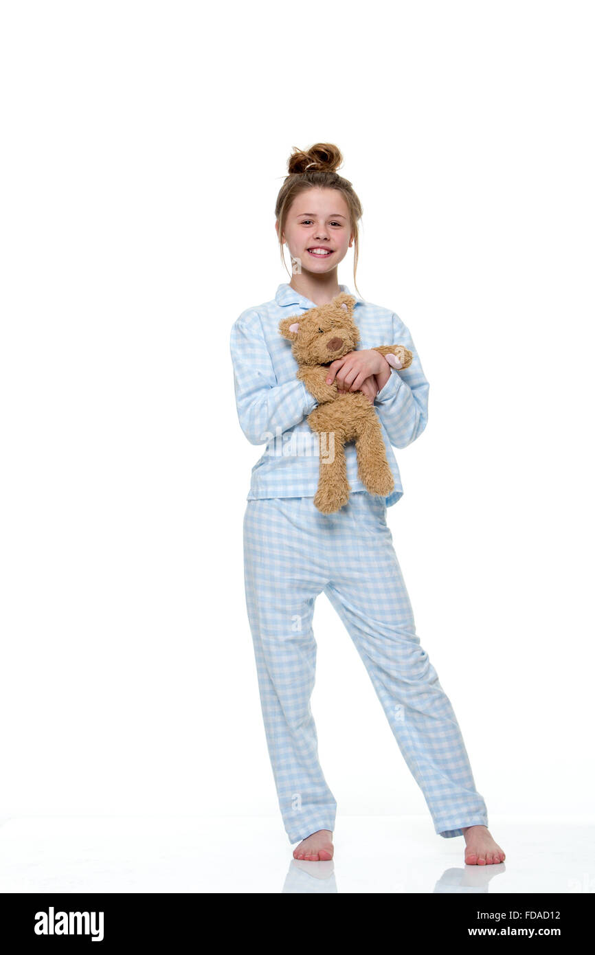 Portrait d'une jeune fille prête à lit dans la lingerie, avec un ours en peluche. L'image a un fond blanc et la jeune fille sourit Banque D'Images