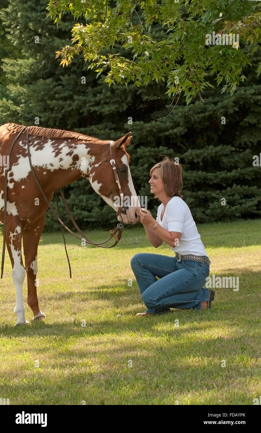 Femme touchent doucement sur le nez du cheval pinto Banque D'Images