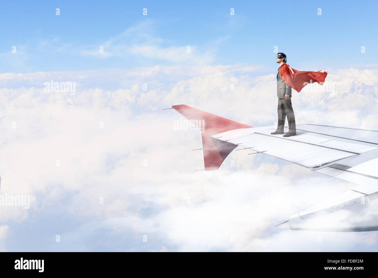 Jeune homme super héros sur le bord d'aile d'avion Banque D'Images