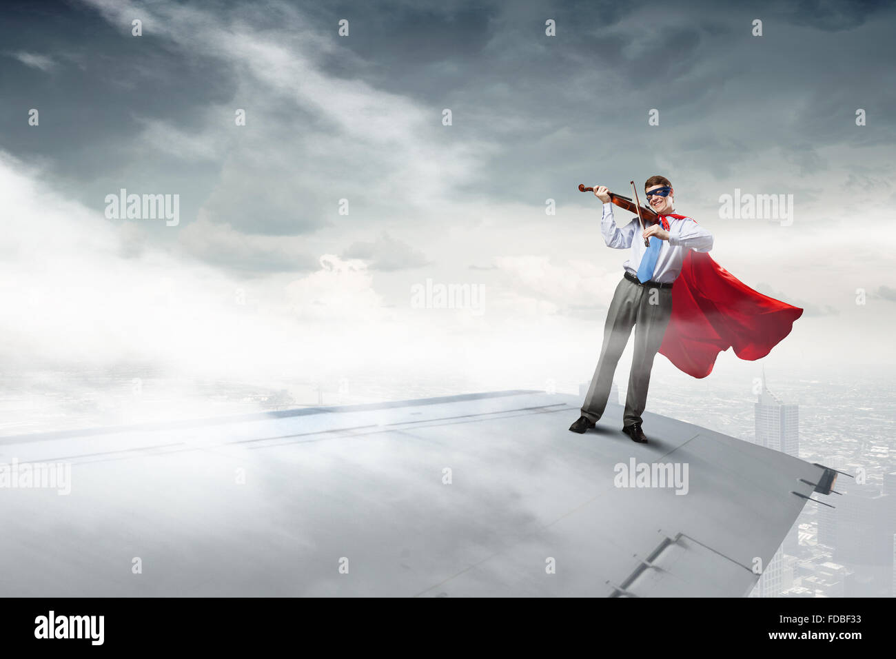 Jeune homme super héros sur le bord d'aile d'avion jouer du violon Banque D'Images