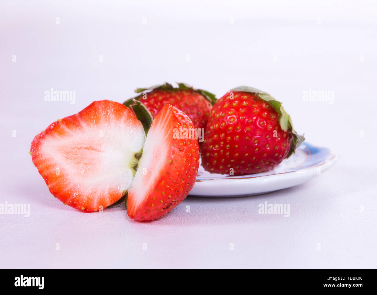 Une fraise coupé en deux et deux fraises derrière cette plus dans un petit plat Banque D'Images