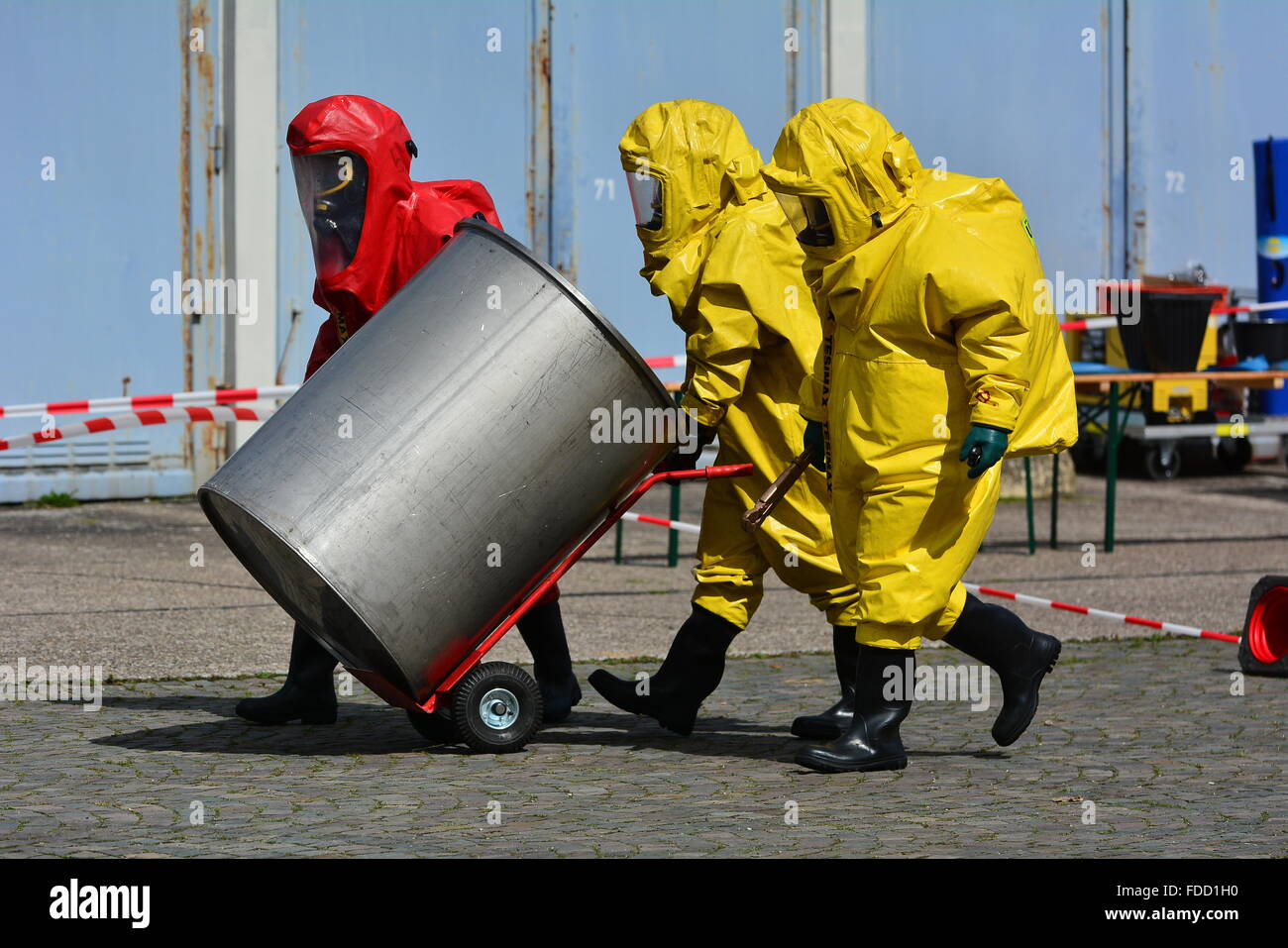 Travailleurs en uniforme de protection masque,transport,gants et bottes de barils de produits chimiques Banque D'Images