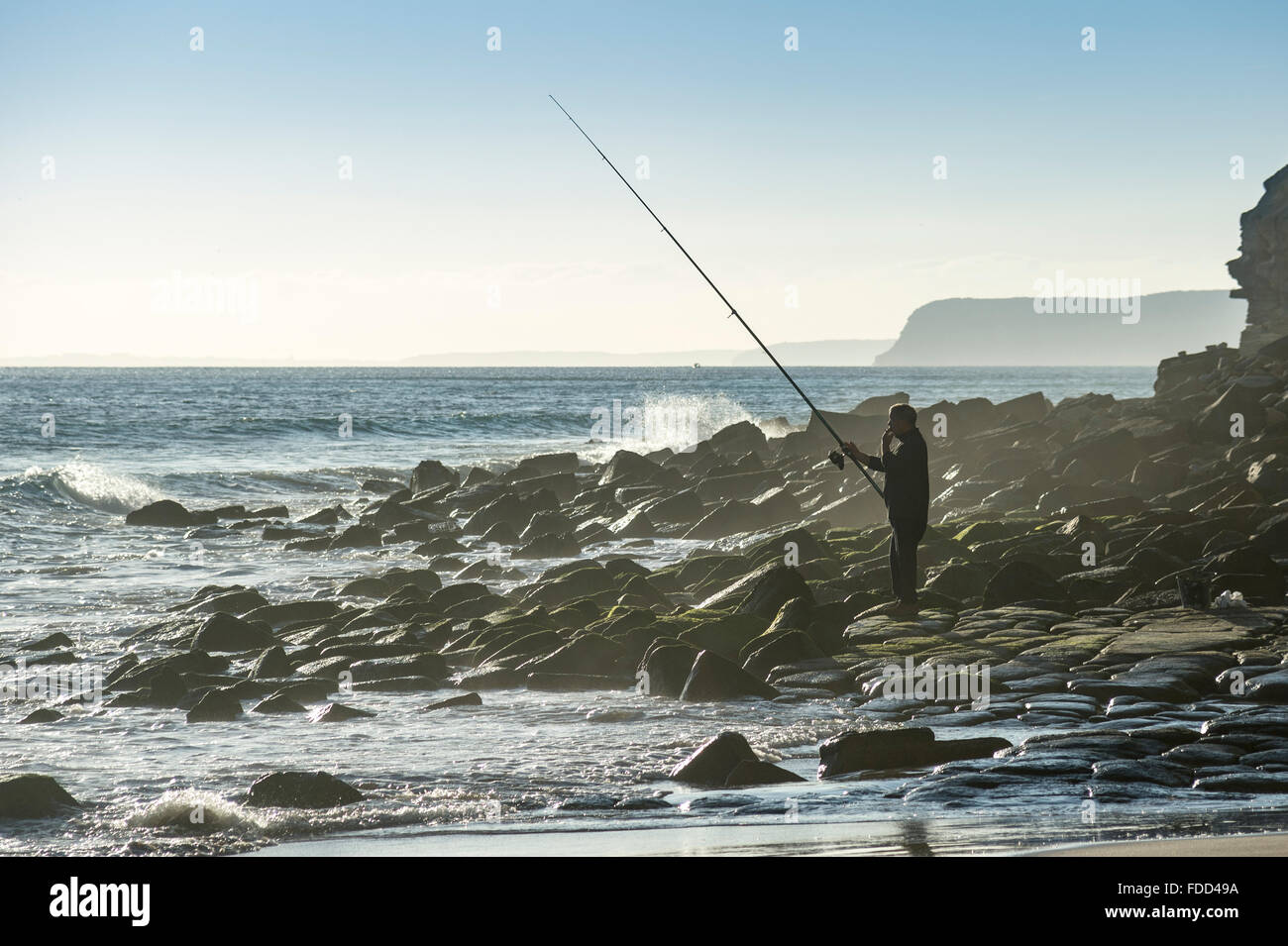 L'homme pêche en mer des rochers au Praia do Porto de Mos, le Portugal. Banque D'Images