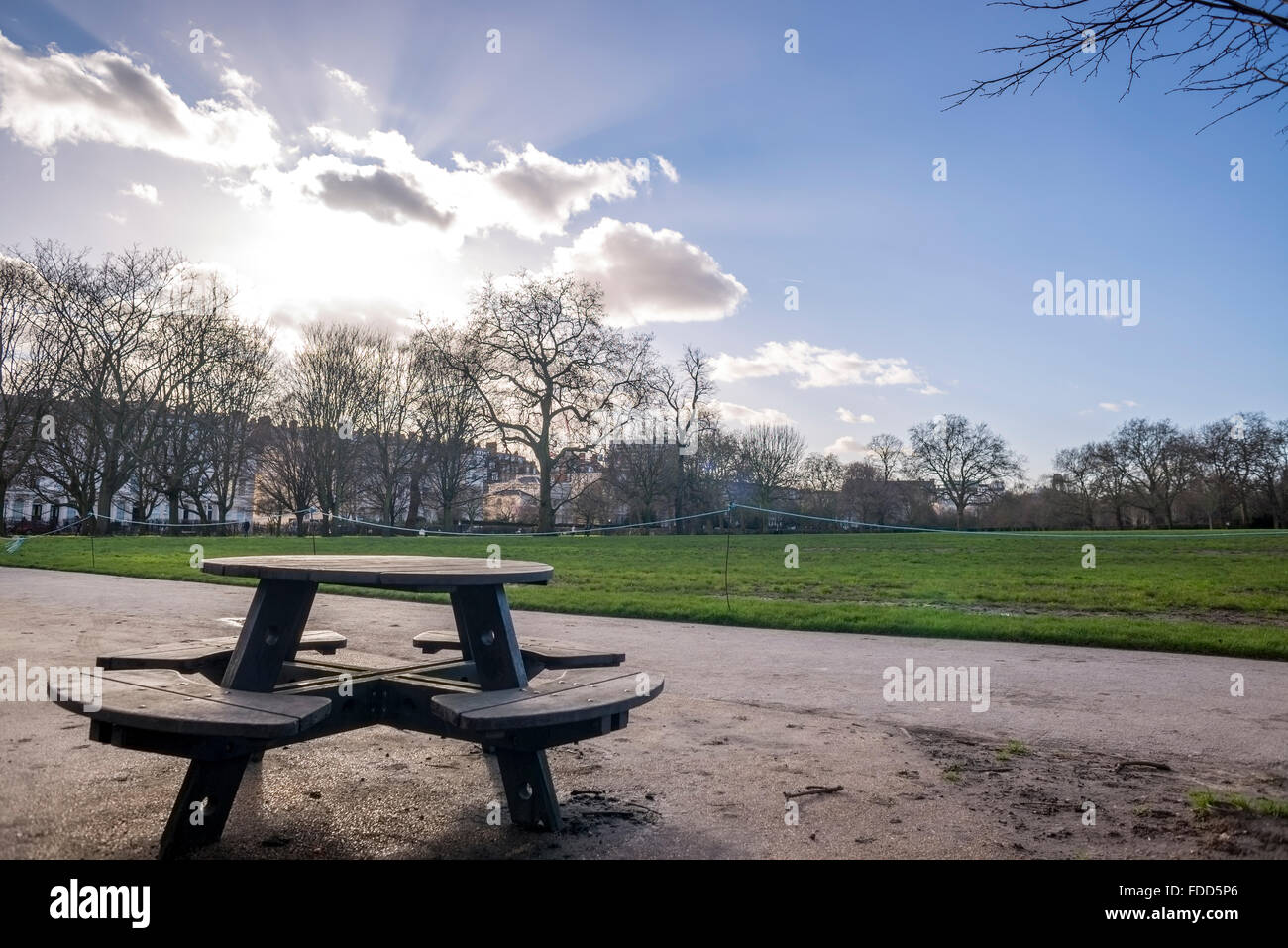 Banc de parc contre le soleil, nuages et ciel bleu Banque D'Images