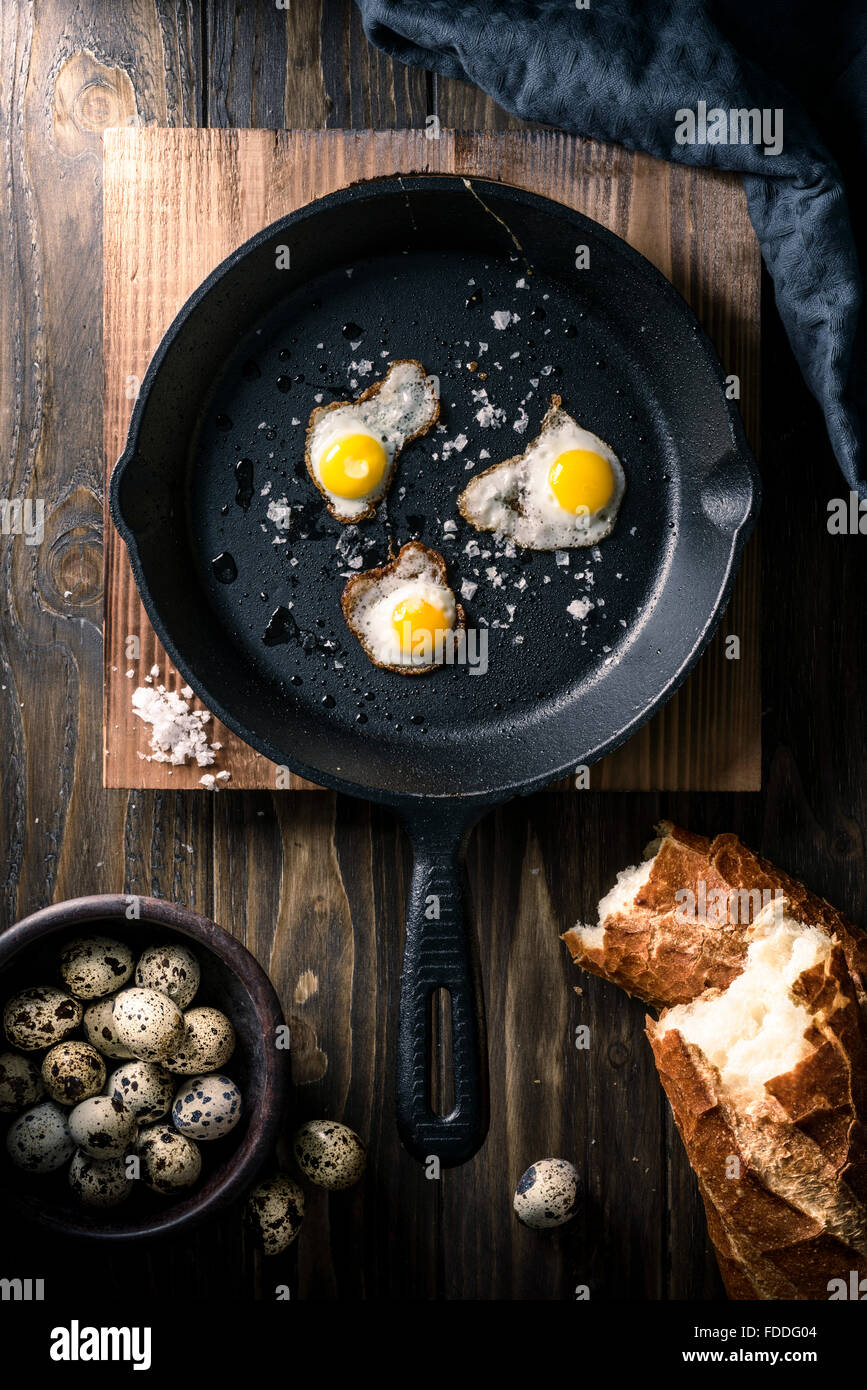 Oeufs de caille frit dans une poêle en fonte avec du pain croustillant Banque D'Images