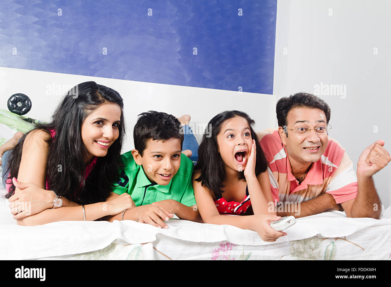 4 personnes Chambre pour enfants et parents couché à regarder la télévision de divertissement Banque D'Images
