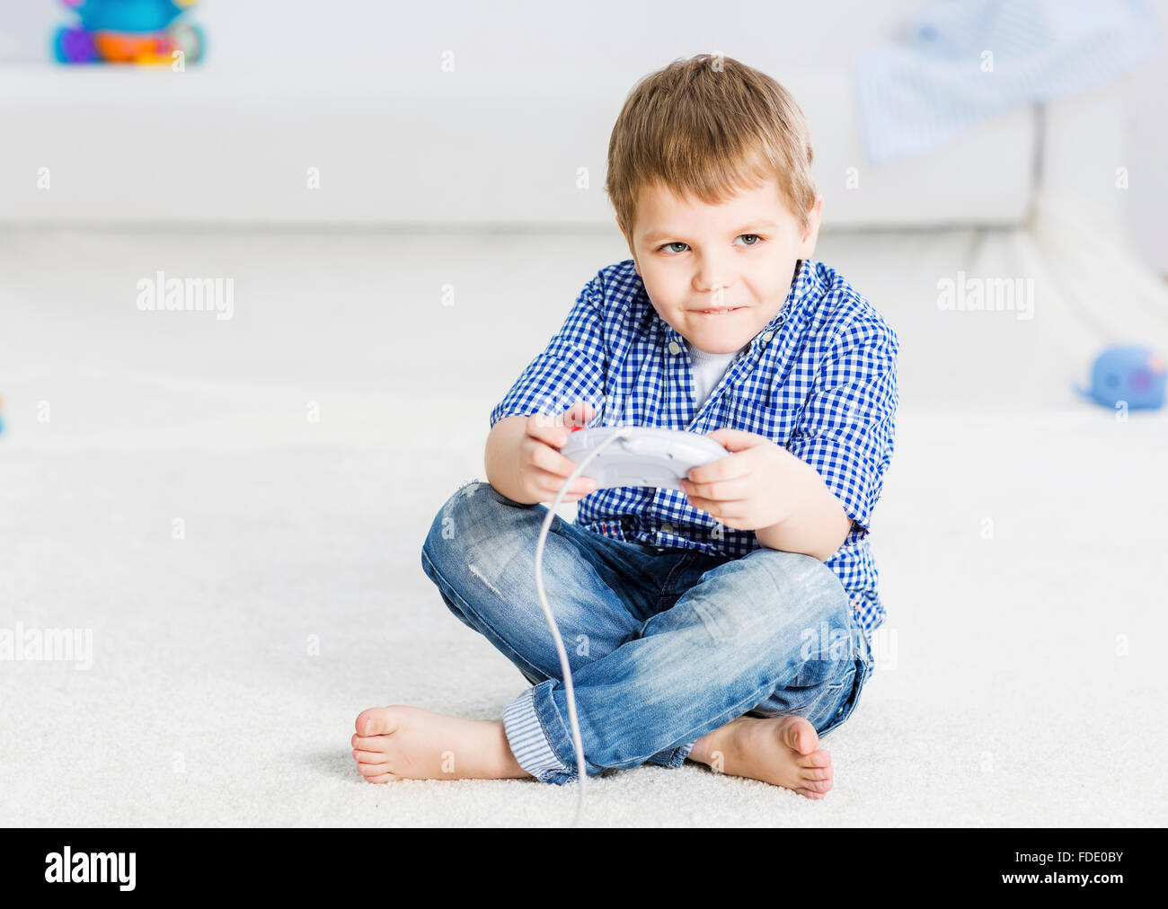 Garçon assis sur le plancher et palying avec joystick Banque D'Images
