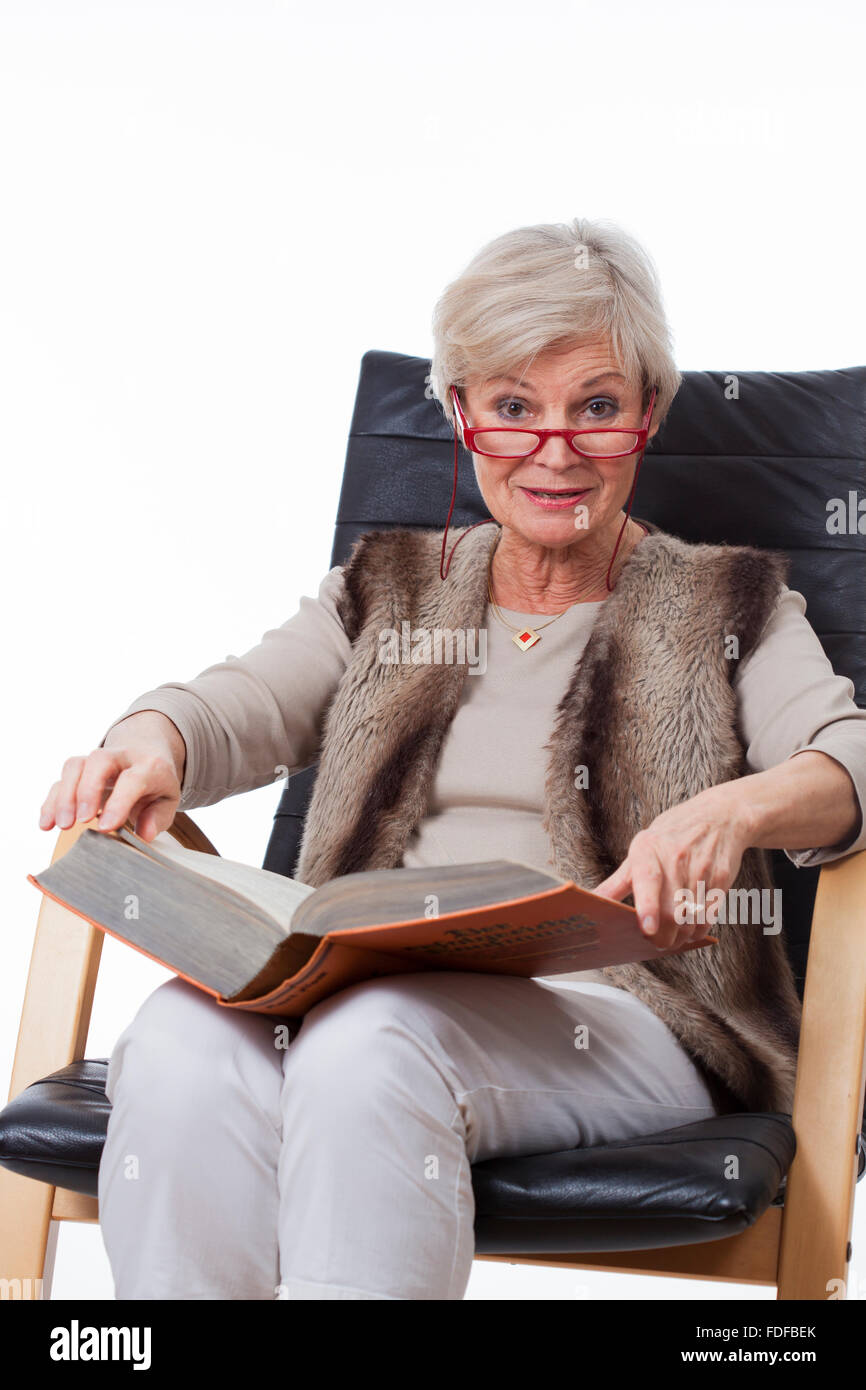 Ancien senior woman reading book in chair Banque D'Images