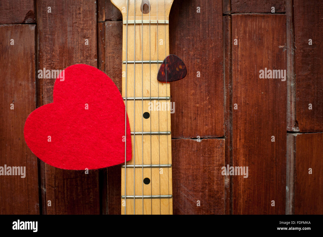 Manche de guitare avec cœur rouge sur fond de bois Banque D'Images