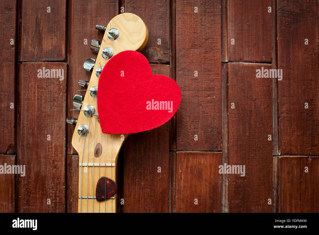 Tête de guitare avec cœur rouge sur fond de bois Banque D'Images