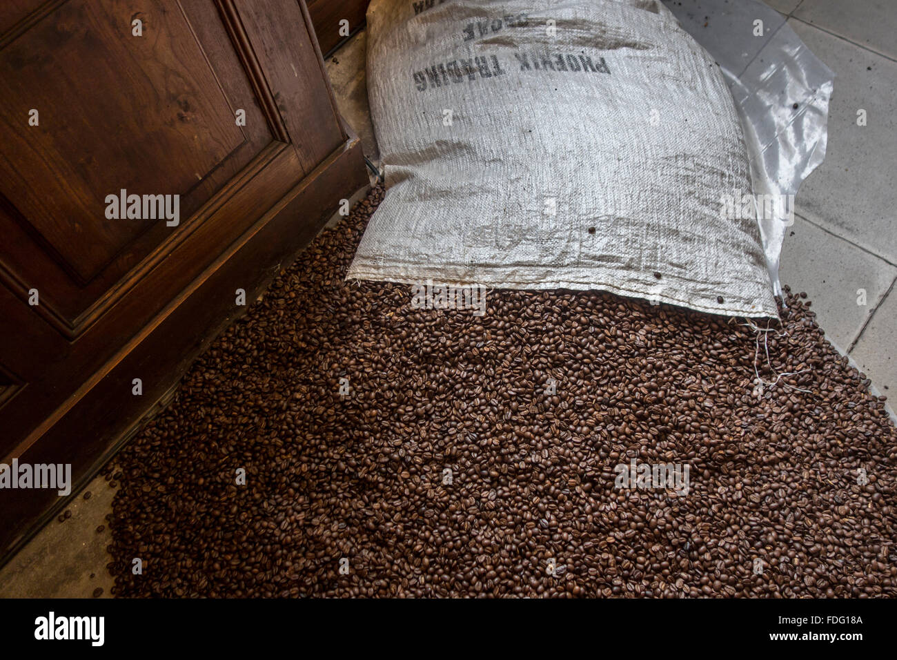 Contenu du sac avec les grains de café torréfiés répartis sur marbre Banque D'Images