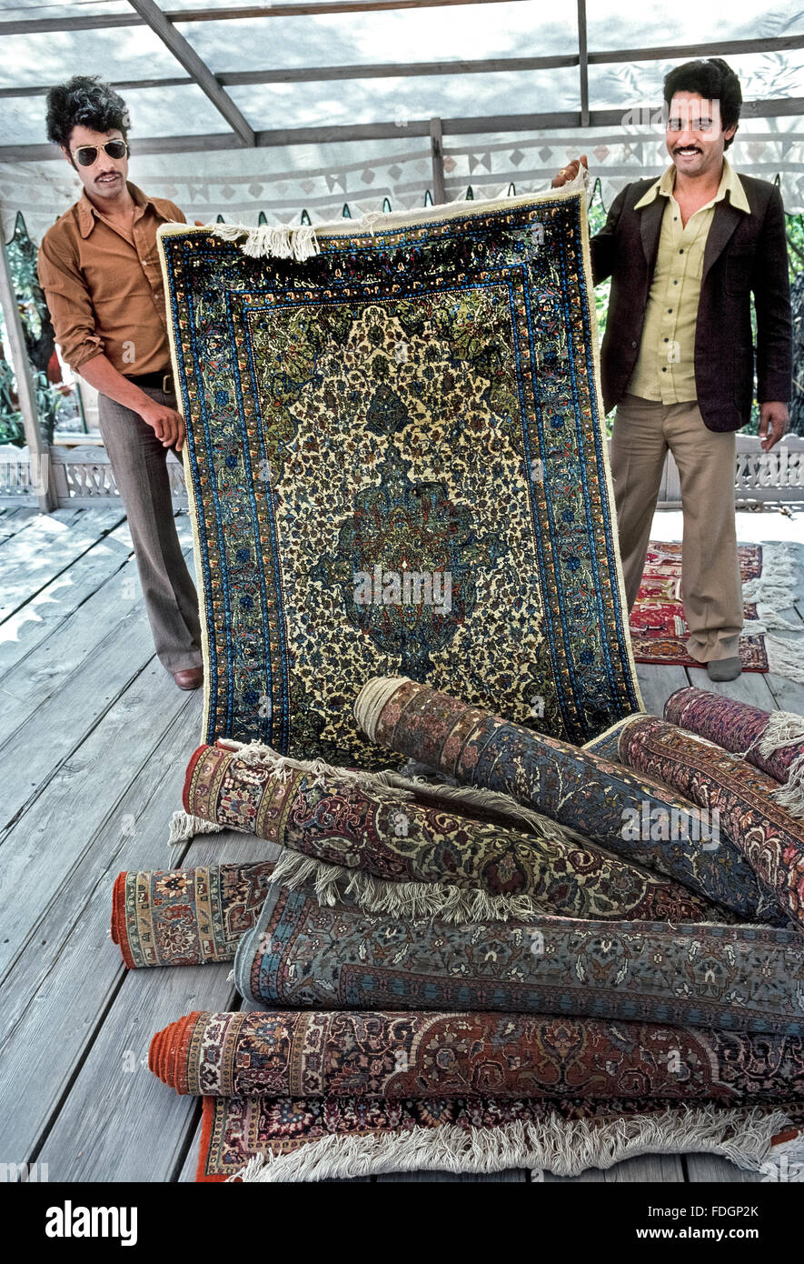Deux vendeurs Kashmiri fièrement tissés à la main traditionnelle de tapis orientaux aux visiteurs à le lac Dal à Srinagar dans l'Inde de la région de Cachemire en Asie du Sud. Banque D'Images
