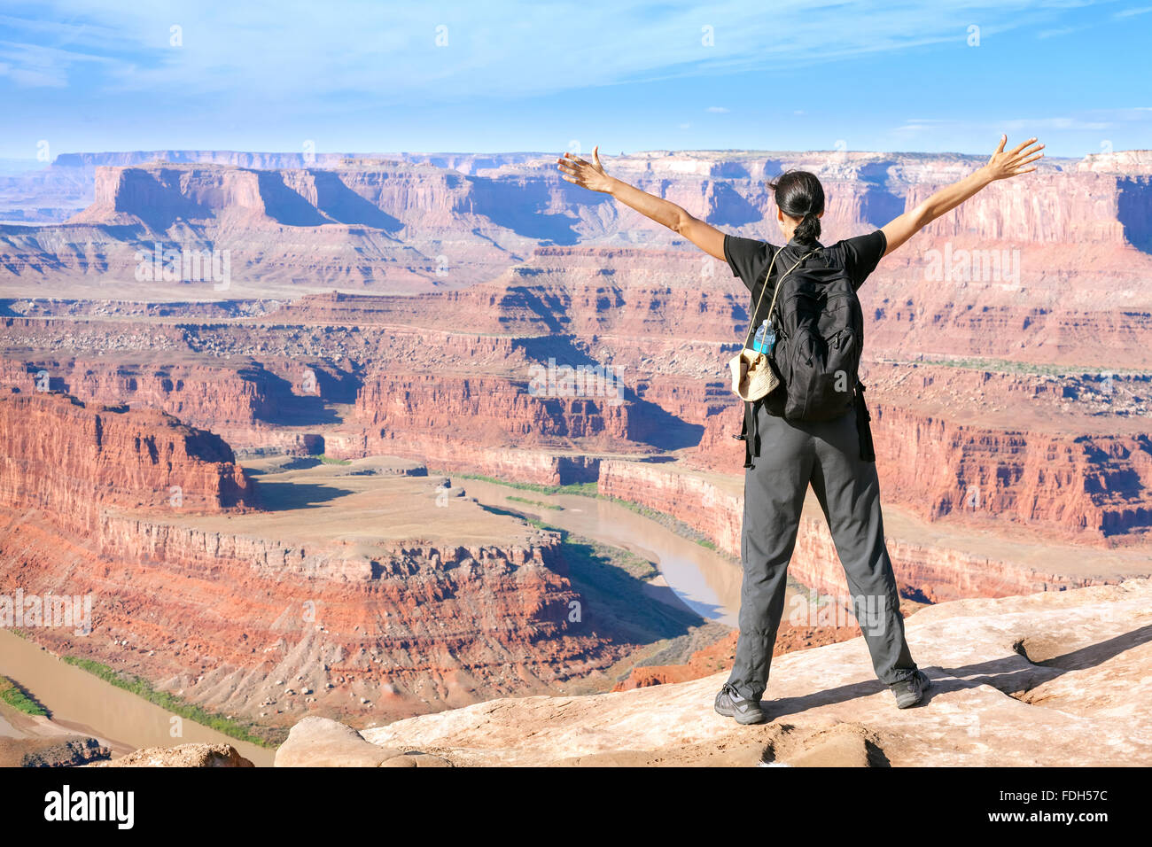 Femme debout au bord d'une falaise avec les mains en l'air, de l'Utah, USA. Banque D'Images