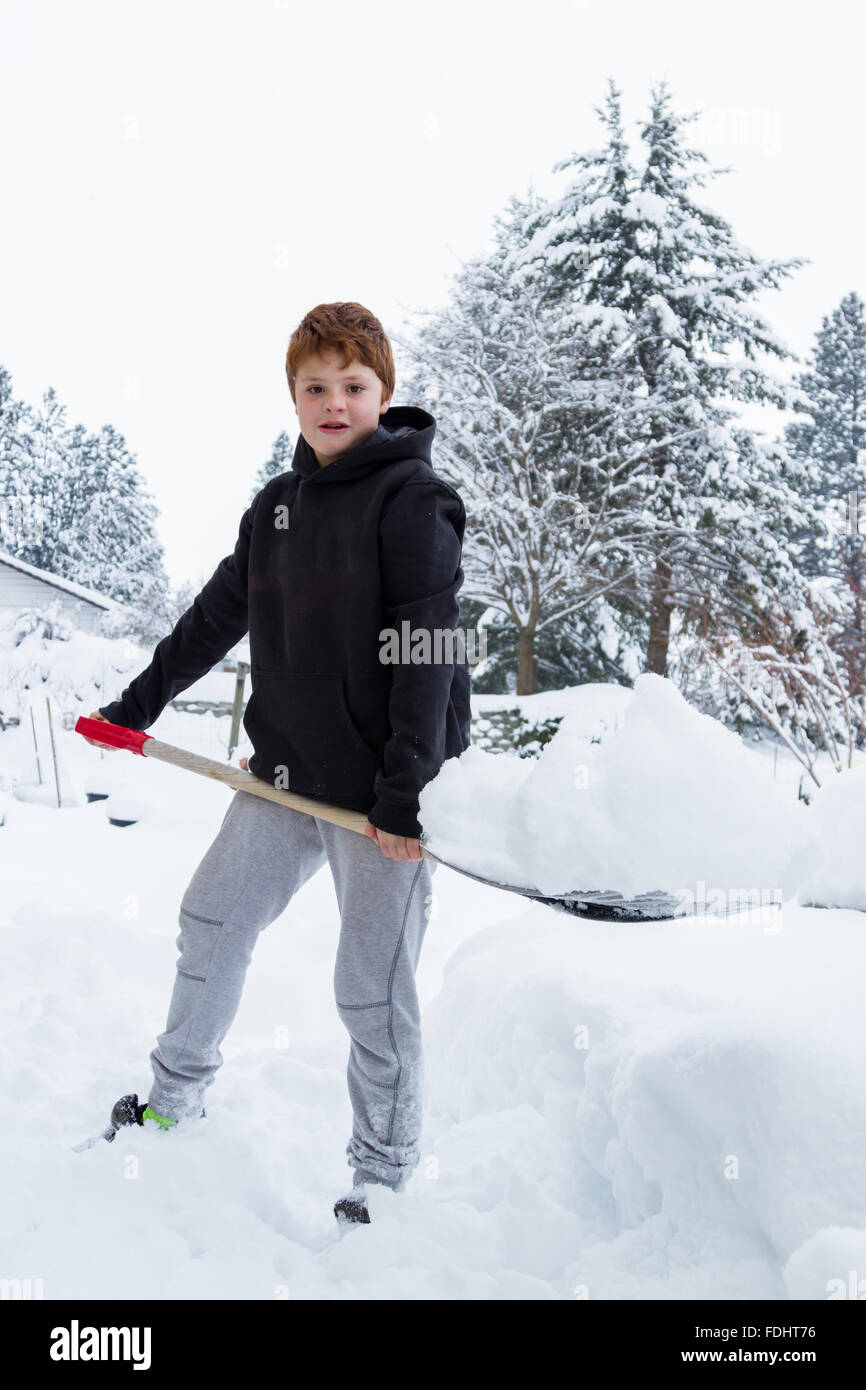 Jeune garçon pelleter la neige du devant de l'entrée de sa maison Banque D'Images