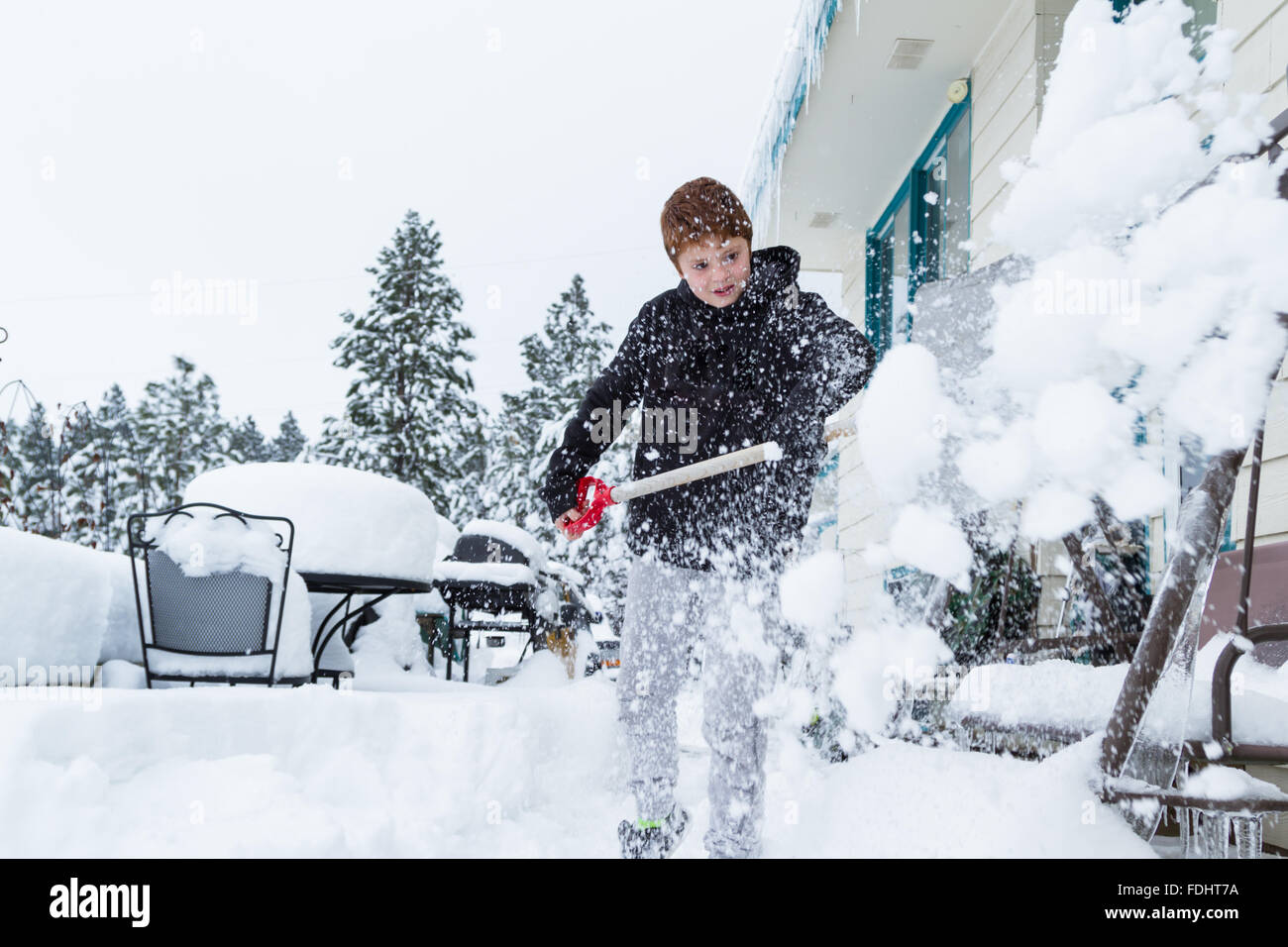 Jeune garçon pelleter la neige du devant de l'entrée de sa maison Banque D'Images