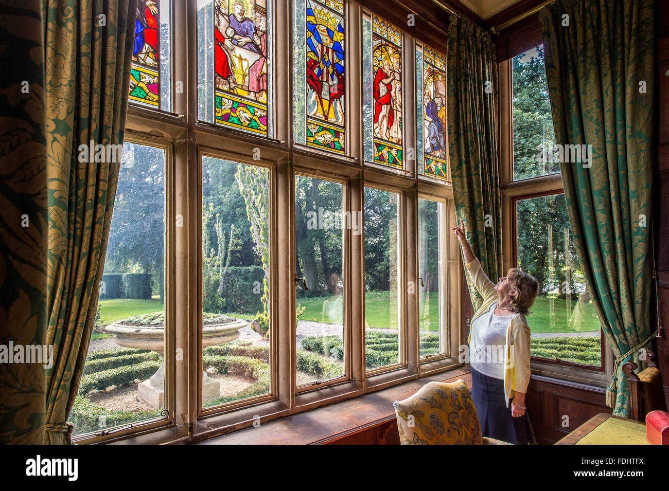 Femme montrant du doigt le verre décoratif dans windows Kiplin Hall dans le Yorkshire du Nord. Banque D'Images