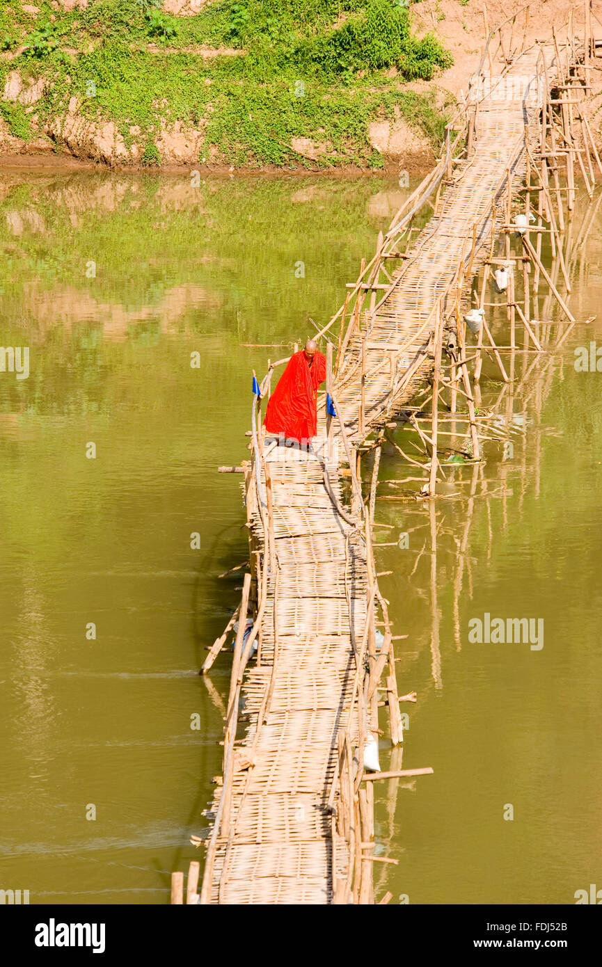 Un moine marchant sur un pont en bambou à Luang Prabang, Laos Banque D'Images