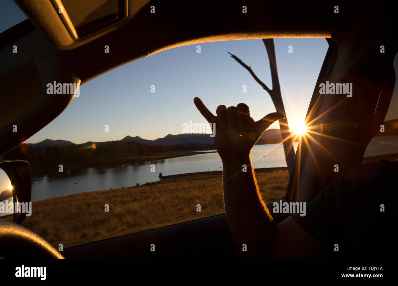 Homme assis dans une voiture faisant un signe Shaka, Queensland, Australie Banque D'Images
