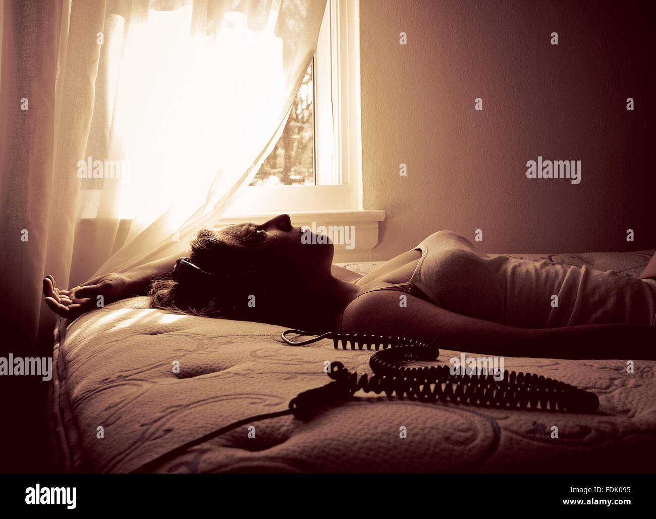 Woman lying on bed listening to music with headphones Banque D'Images