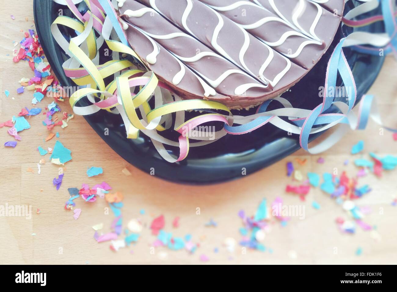 Gâteau au chocolat, entouré par des serpentins et confettis Banque D'Images