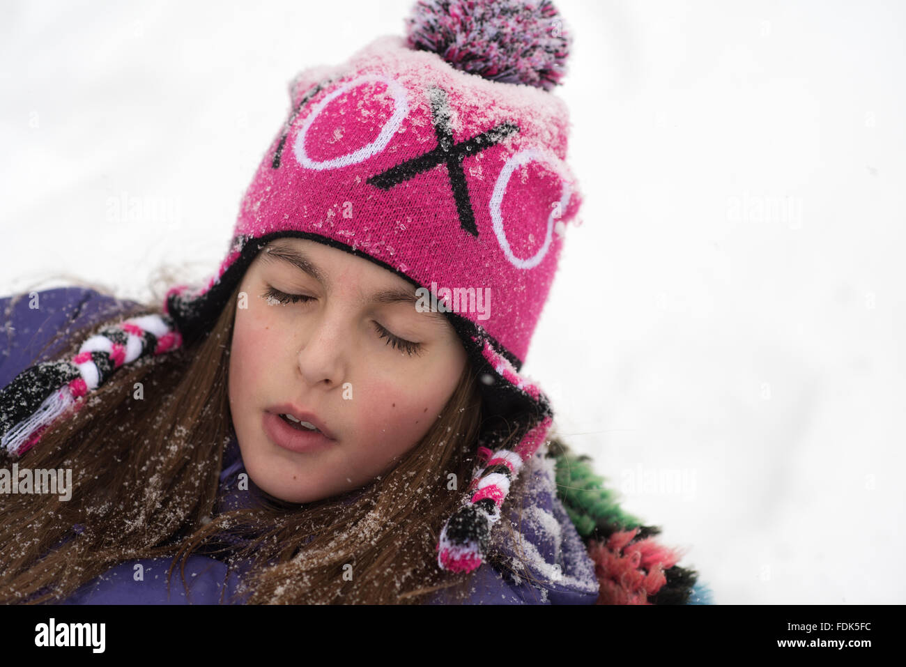 Girl couché dans la neige avec ses yeux fermés Banque D'Images