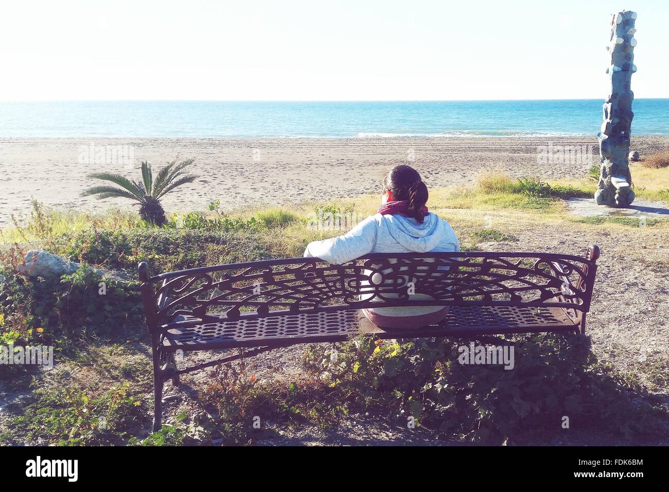 Rear view of woman sitting on bench at beach, Malaga, Espagne, Andaulcia Banque D'Images