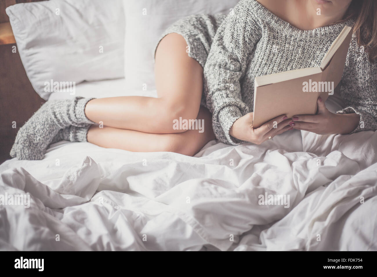 Vue latérale d'une femme allongée sur un lit un livre de lecture Banque D'Images