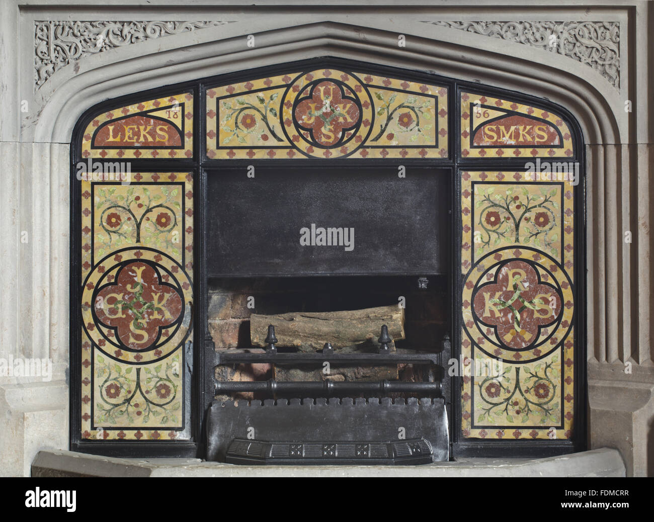1856 Pugin-style fire surround avec marbre de couleur portant les initiales de Sir James Kay Shuttleworth a cinq enfants, dans le hall d'entrée à Gawthorpe Hall, Lancashire. Banque D'Images