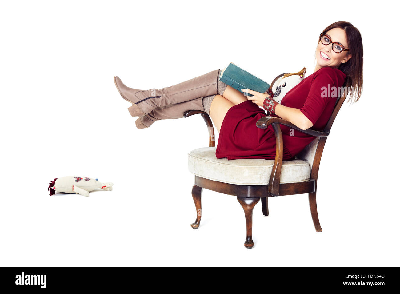 Studio shot of attractive woman se détend avec un livre dans un fauteuil. Banque D'Images