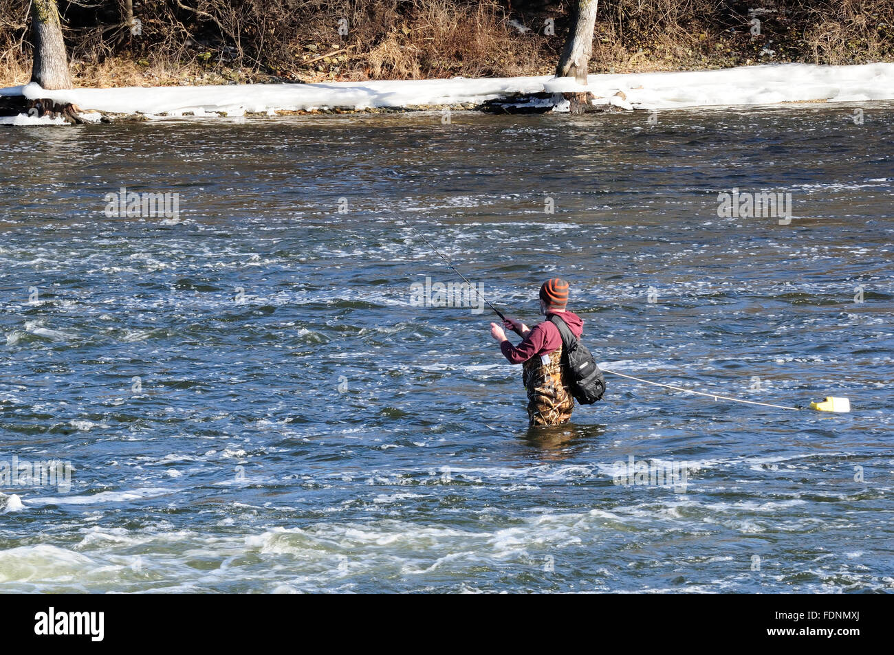 L'homme dans les bottes cuissardes de pêche dans la rivière à un barrage. Banque D'Images