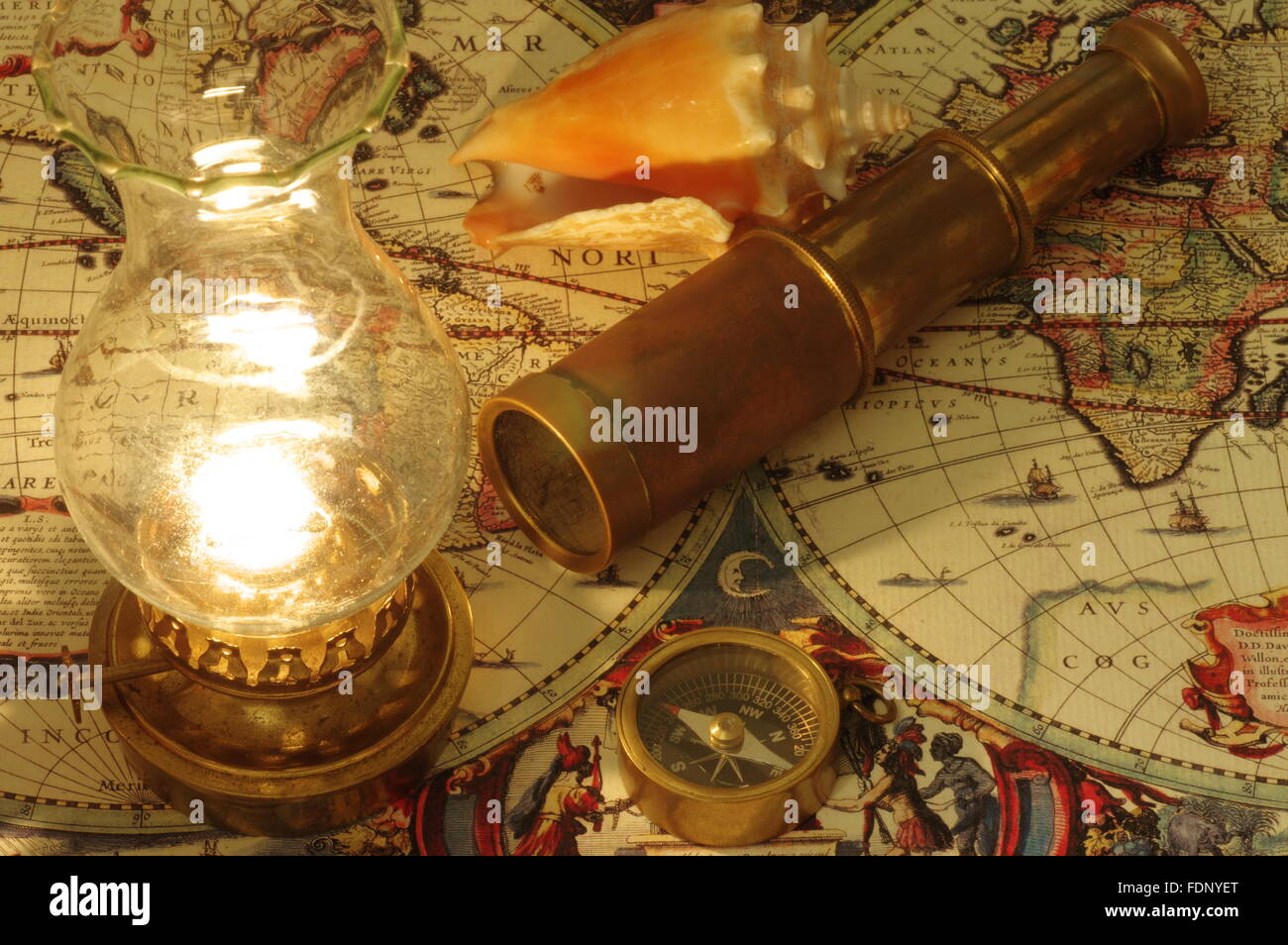 Vieux télescope, boussole, lampe au kérosène et coquillage allongé sur une vieille carte du monde. Banque D'Images