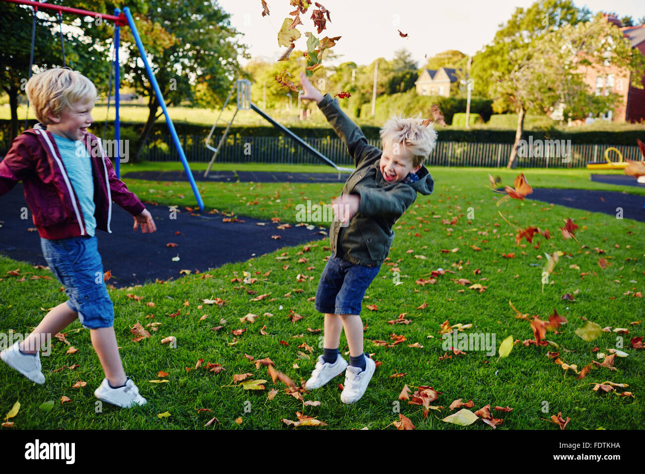 Deux jeunes garçons Jeter feuilles dans le parc d'amusement. Banque D'Images