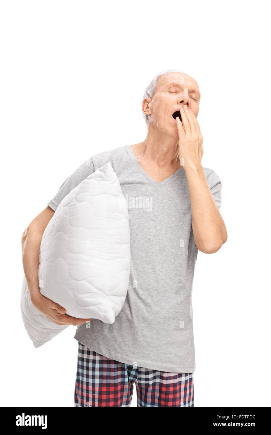 Shot vertical d'un sleepy man holding a white pillow et le bâillement isolé sur fond blanc Banque D'Images