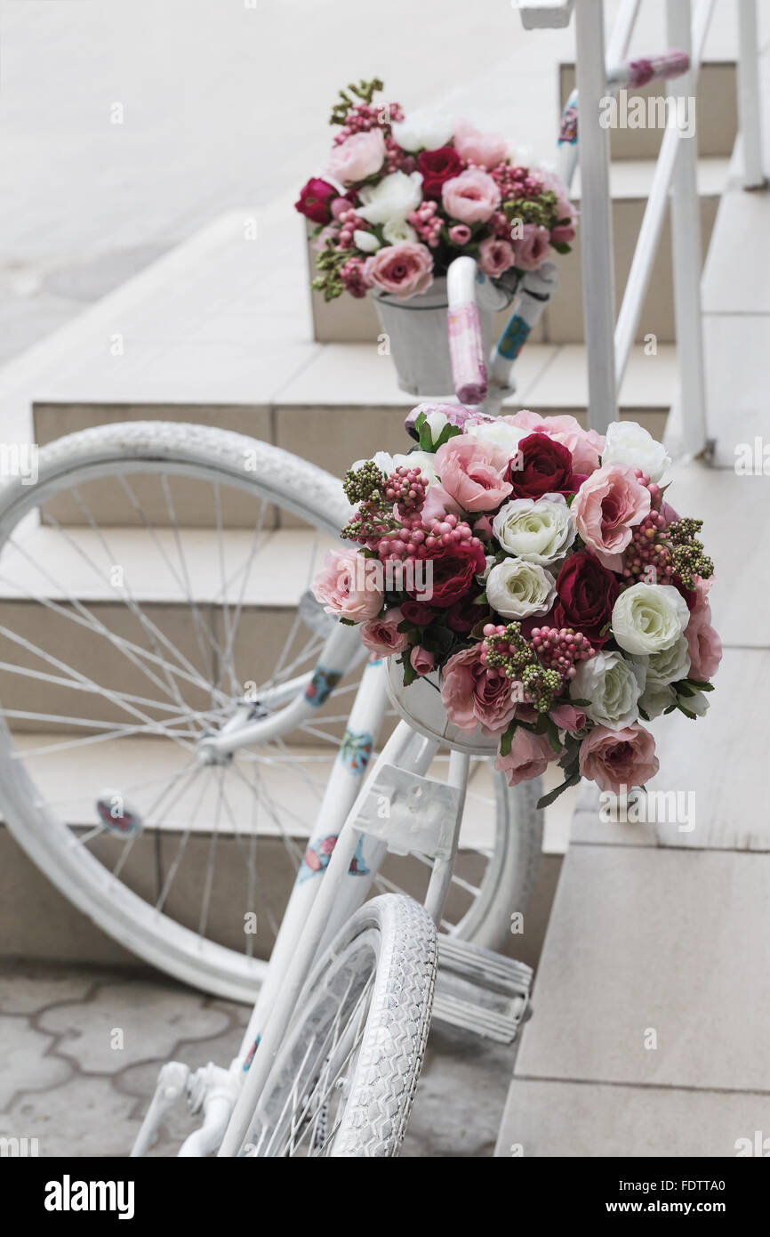 Creative bouquet de fleurs artificielles colorées sur de vieux vélo blanc. Focus sélectif et de l'espace dans la zone de flou composition Banque D'Images