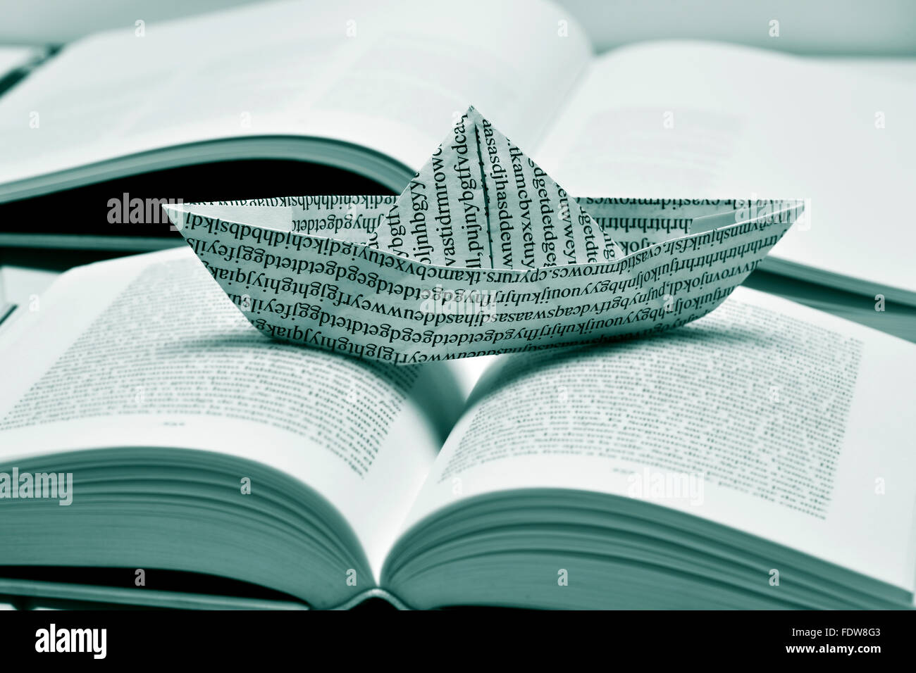 Libre d'un bateau de papier, fait avec un papier imprimé avec des mots non-sens, sur un livre ouvert, en noir et blanc Banque D'Images