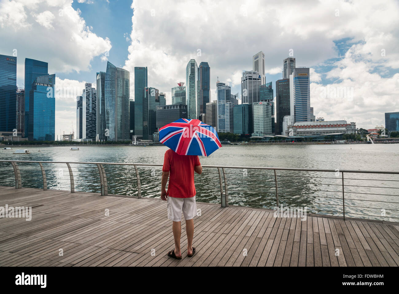 Un homme l'affichage de la ville de Singapour bâtiments sur Marina Bay et tenant un parapluie Union Jack Banque D'Images