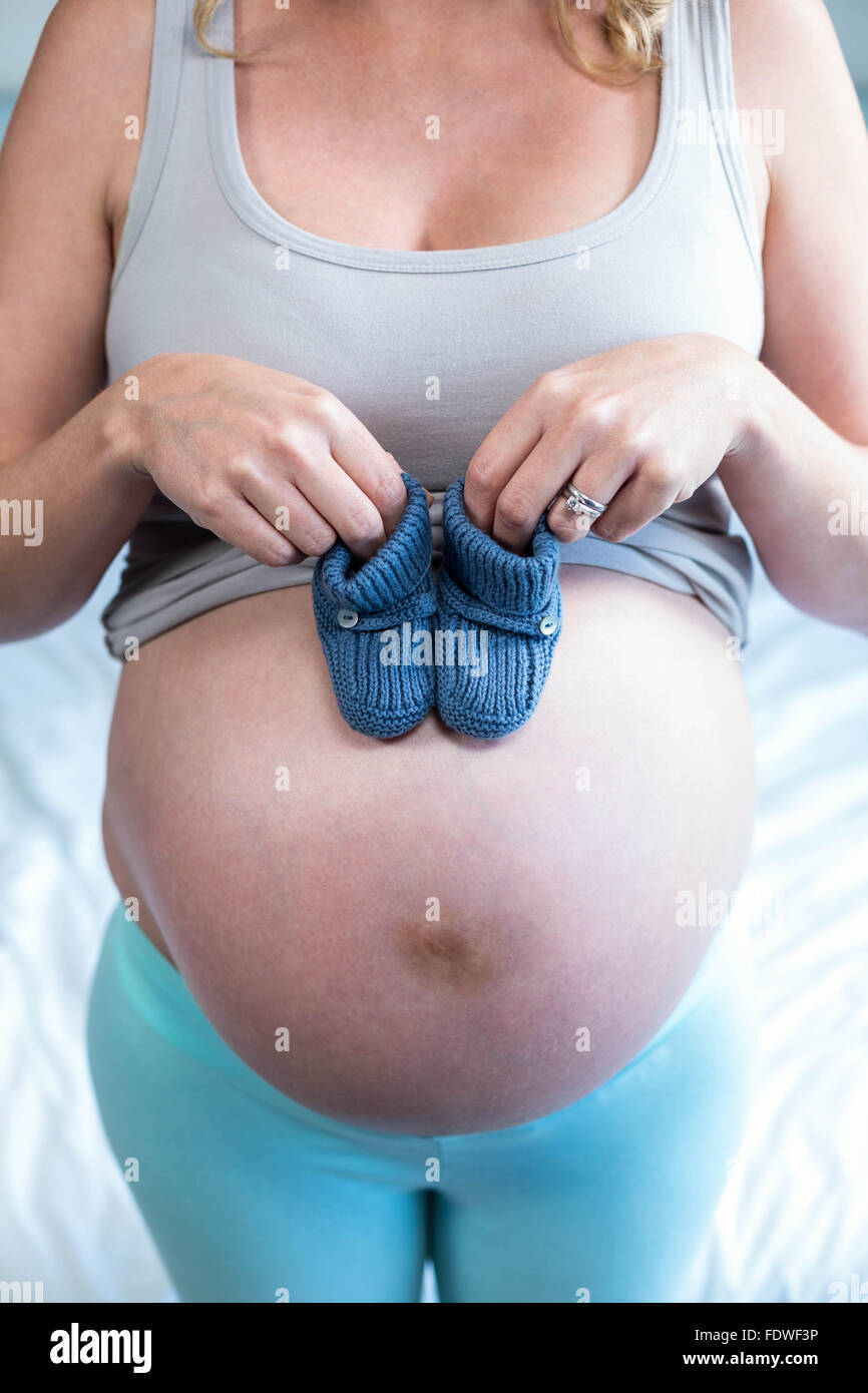 Femme enceinte avec chaussons tricotés sur son ventre Banque D'Images