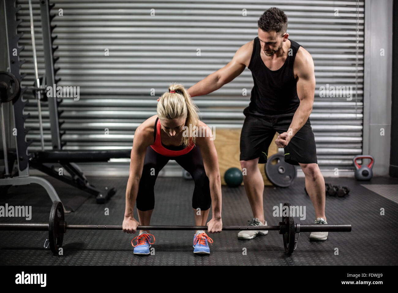 Trainer helping woman with barbell levage Banque D'Images