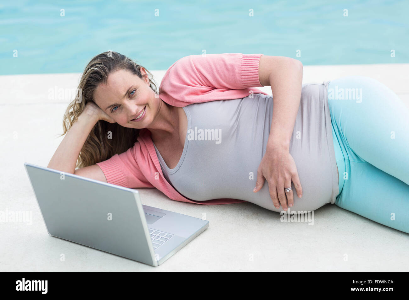 Femme enceinte à l'extérieur de détente using laptop Banque D'Images