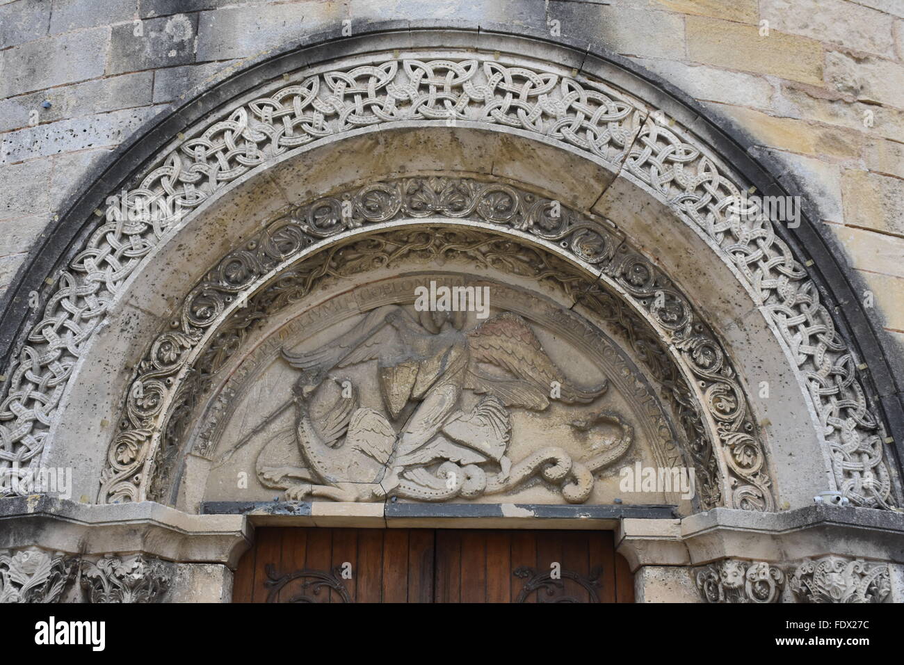 Tympan de l'église de Saint-Michel dans la banlieue d'Angoulême France, montrant l'Archange St Michel terrassant le dragon Banque D'Images